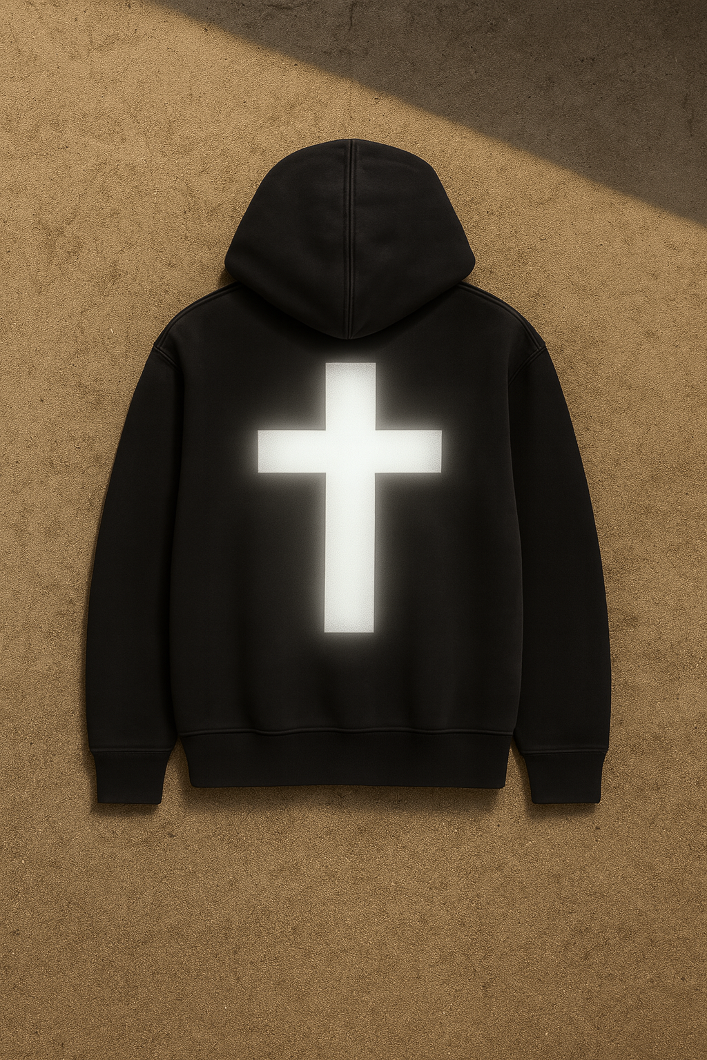 Black hoodie with a reflective white cross on the back against a brown background