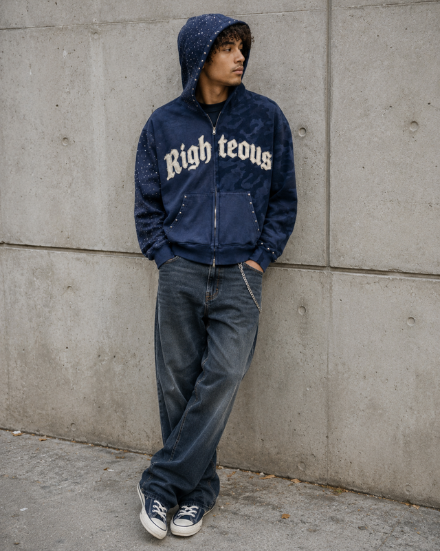 Person wearing a blue jacket with 'Righteous' text, standing against a concrete wall.