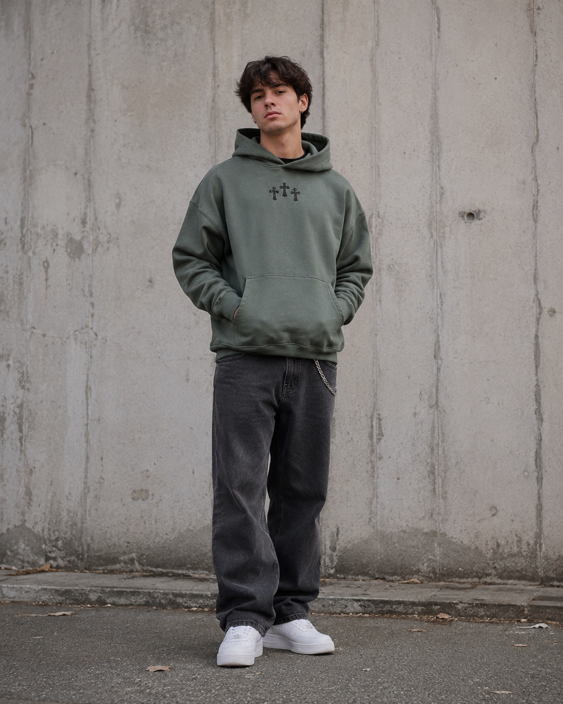 Person wearing a green hoodie with a logo against a concrete wall.