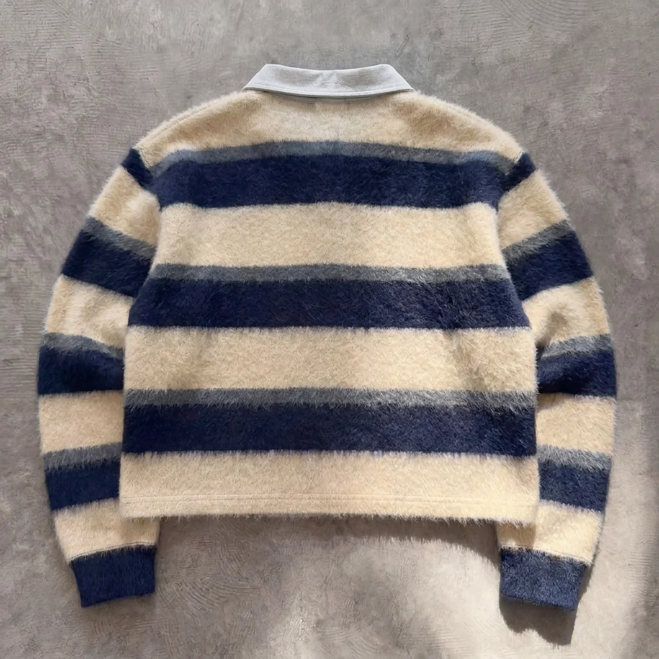 Striped sweater with blue and beige colors on a gray background