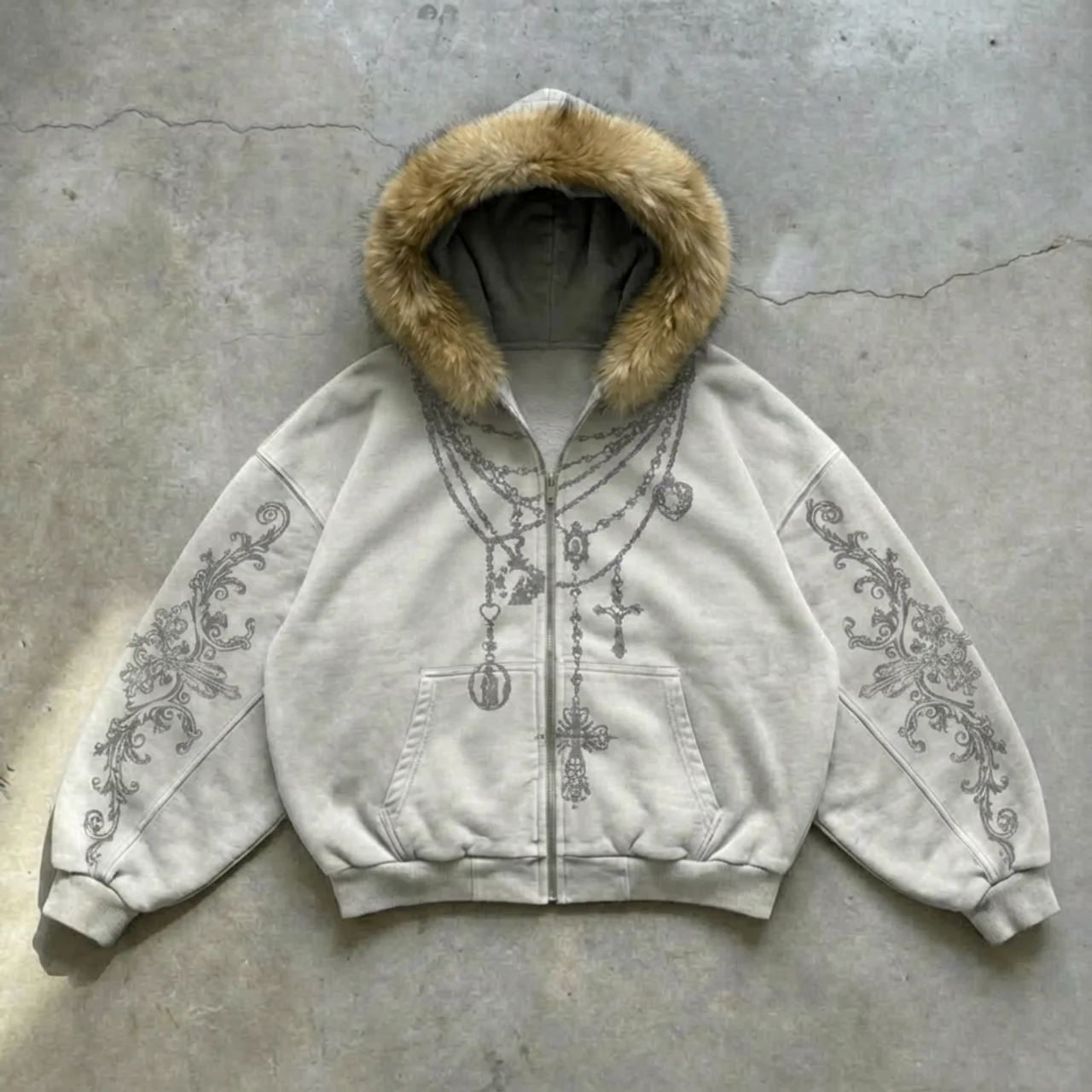 White hoodie with fur hood and intricate designs on a concrete surface