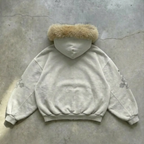 Light gray hoodie with fur hood on a concrete floor
