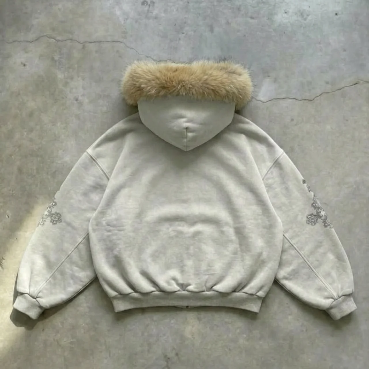 Light gray hoodie with fur hood on a concrete floor