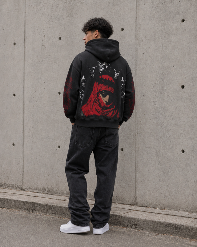 Person wearing a black hoodie with a red graphic design against a concrete wall.