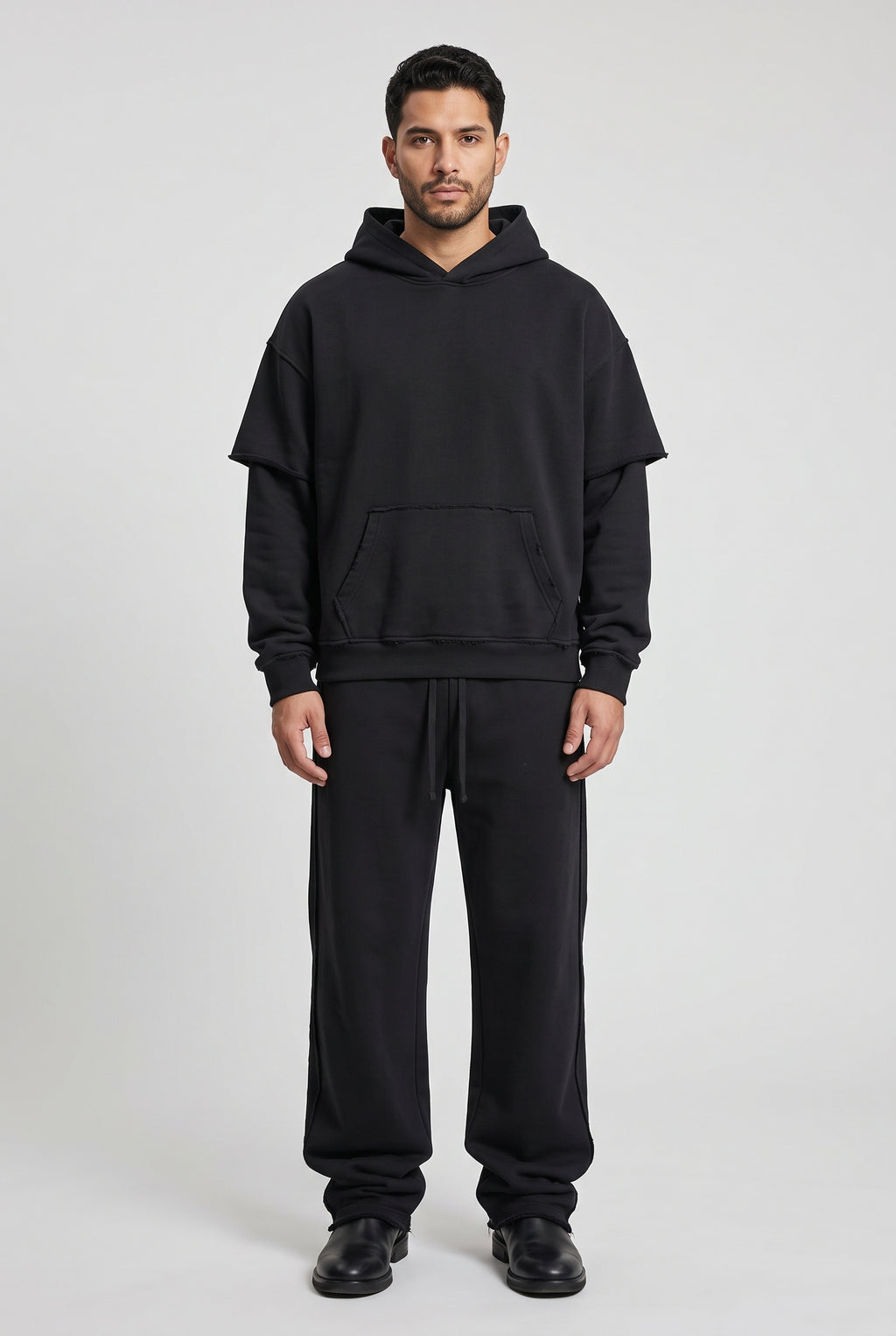 Snow-washed raw edge hoodie and sweatpants set in black, worn together
