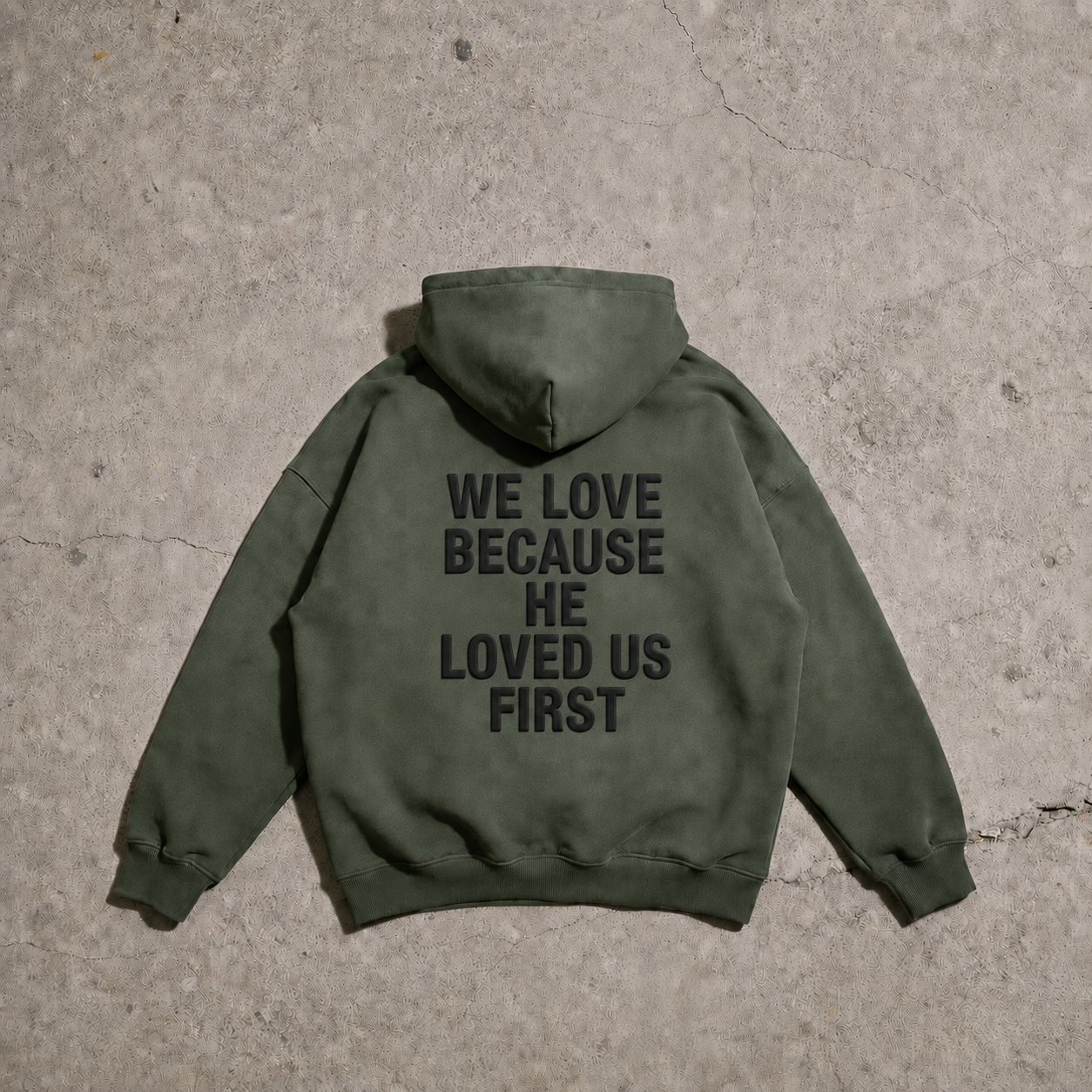 Green hoodie with text on the back on a concrete surface